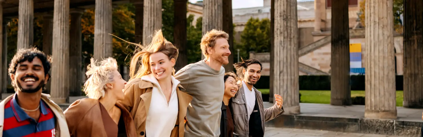 6 Menschen laufen lachend nebeneinander, im Hintergrund ist die alte Nationalgalerie Berlins Bild mit KI erstellt.