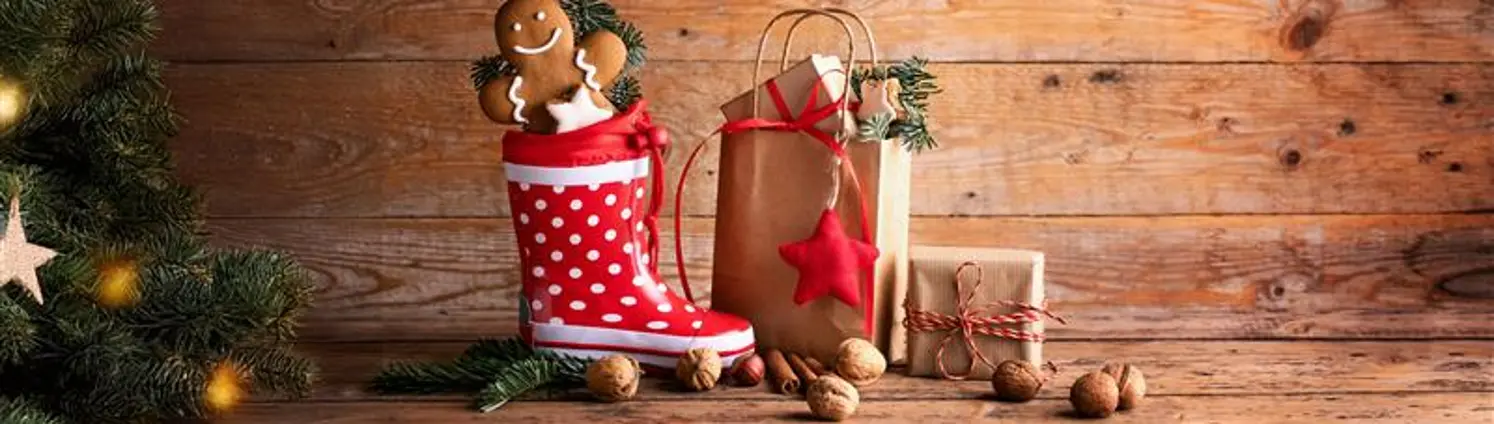 Ein Nikolausstiefel mit Lebkuchen gefüllt steht neben einer Geschenketüte mit Geschenken