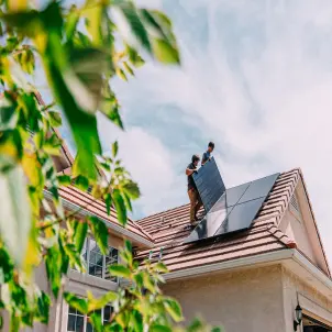 Eine Person bringt eine PV-Anlage auf dem Dach an.