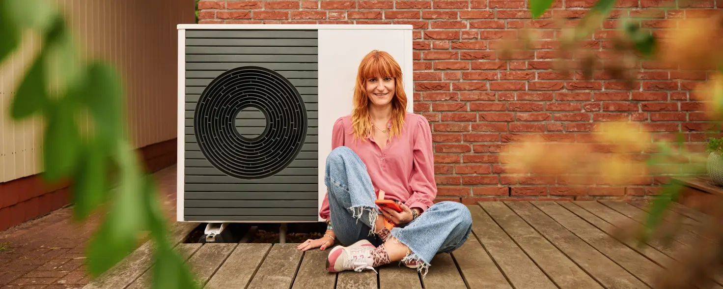 Eine Frau sitzt vor einer Wärmepumpe