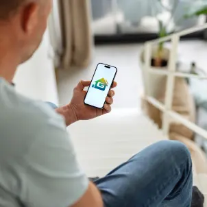 Mann schaut auf den Bildschirm seines Smartphones und öffnet die Energiemanager-App der GASAG