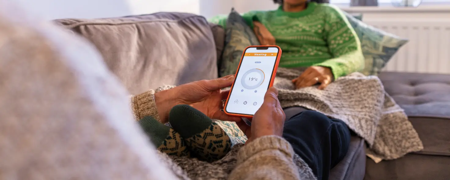 Eine Person liegt auf dem Sofa und hält ein Smartphone in der Hand.