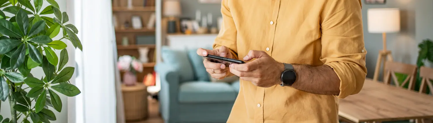 Porträt eines fröhlichen Mannes, der zu Hause ein Smartphone benutzt