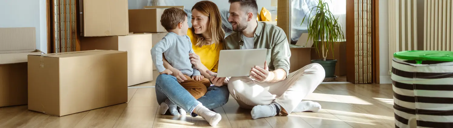 Eine Familie sitzt zwischen Umzugskartons auf dem Boden