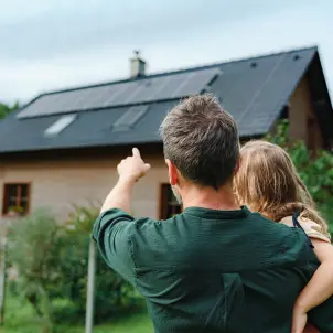 Mann zeigt Kind ihre Photovoltaik-Anlage auf dem Dach