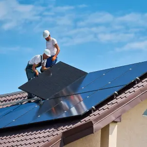 Zwei Männer installieren eine Solaranlage auf dem Dach