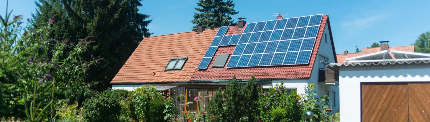 Ein Einfamilienhaus mit Photovoltaik-Modulen auf der einen Hälfte des Daches