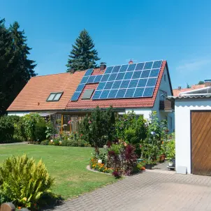 Ein Einfamilienhaus mit Photovoltaik-Modulen auf der einen Hälfte des Daches