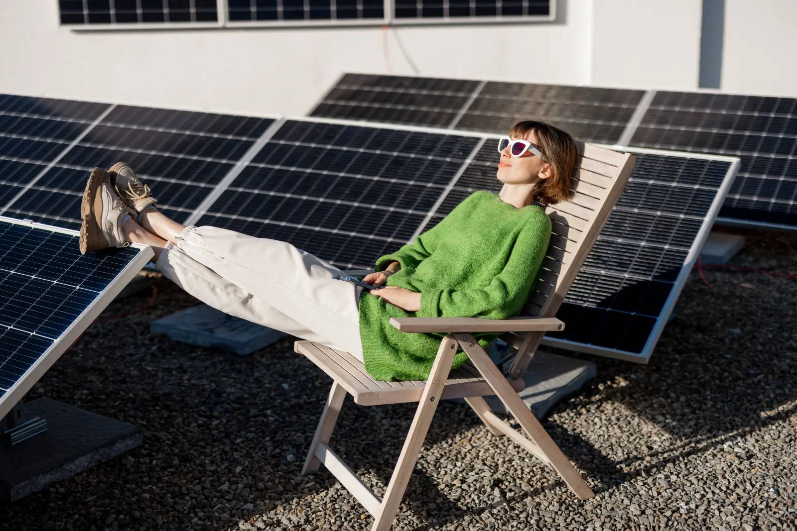 Frau in einem grünen Pullover auf dem Dach ihres Hauses mit einer Solarstation