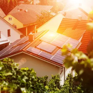 Haus von oben umgeben von Bäumen und Sonnenschein mit Solarthermie auf dem Dach