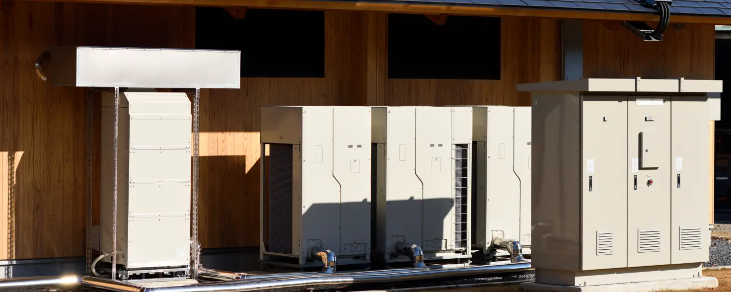 Satteldach mit Photovoltaik-Paneelen und darunter aufgereihten Stromspeicherkästen.
