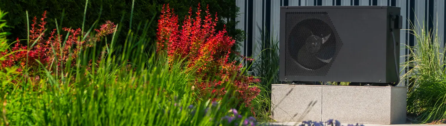 Wärmepumpeneinheit die von dekorativen Pflanzen umgeben ist.