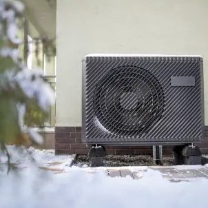 Wärmepumpe an einer Hauswand im Schnee