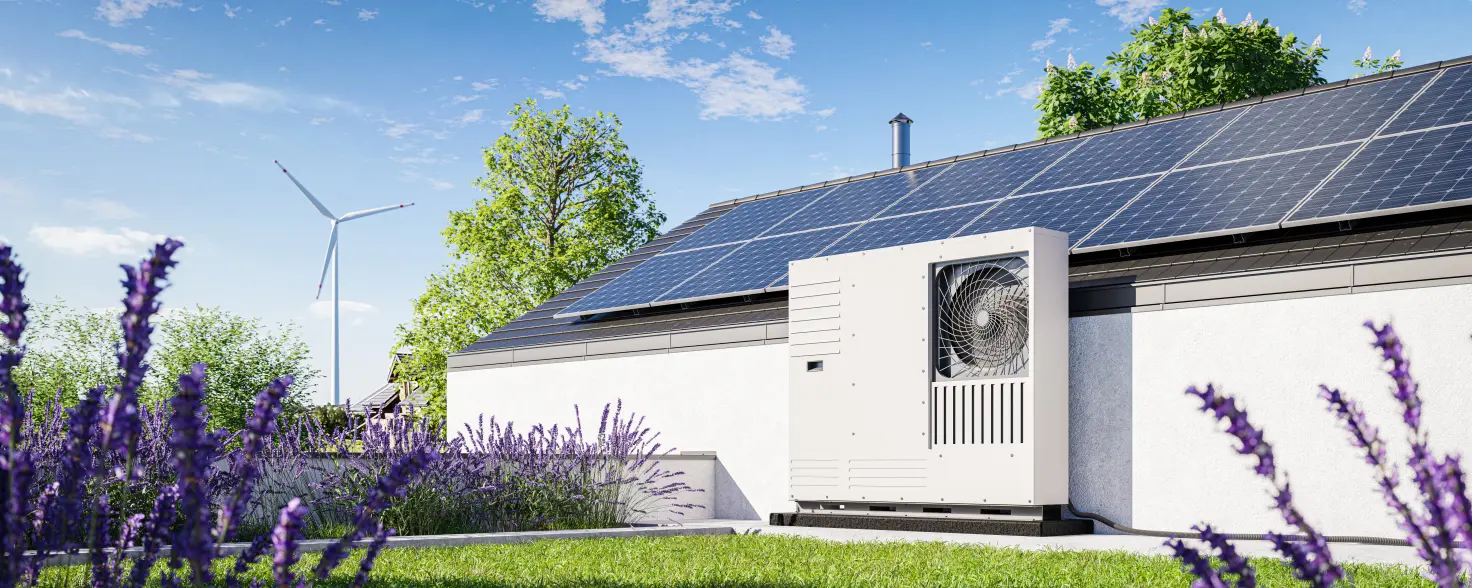 Grüner Garten mit installierter Wärmepumpe und Photovoltaik-Paneele auf dem Dach eines Einfamilienhauses.