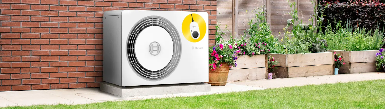 Eine Wärmepumpe steht im Garten neben Pflanzenkübeln