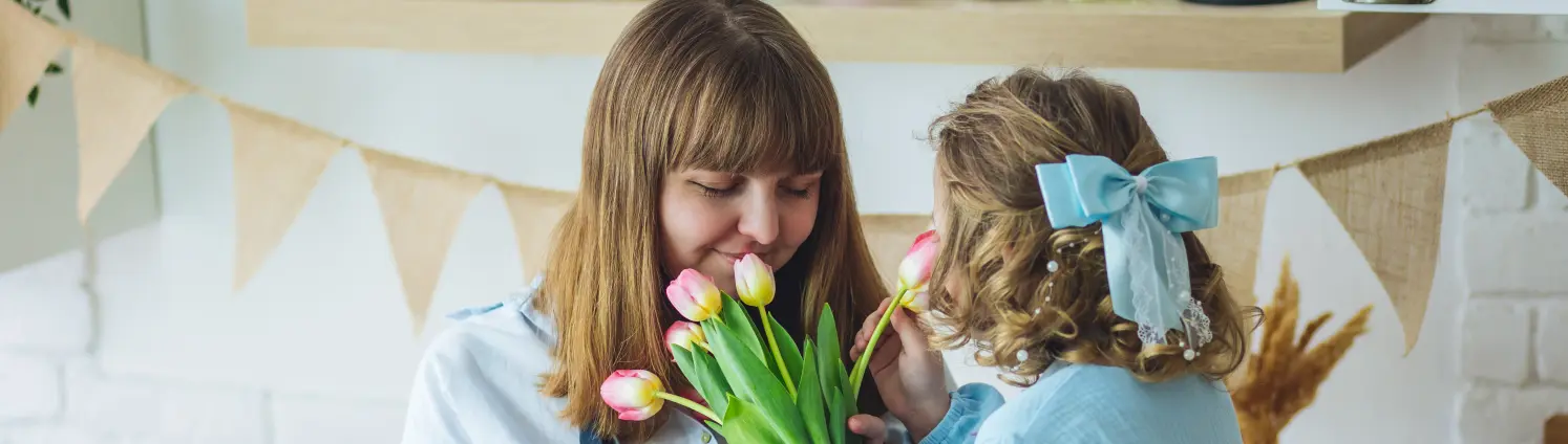 Mutter und Tochter stehen in der Küche und riechen an frischen Tulpen im Frühjahr