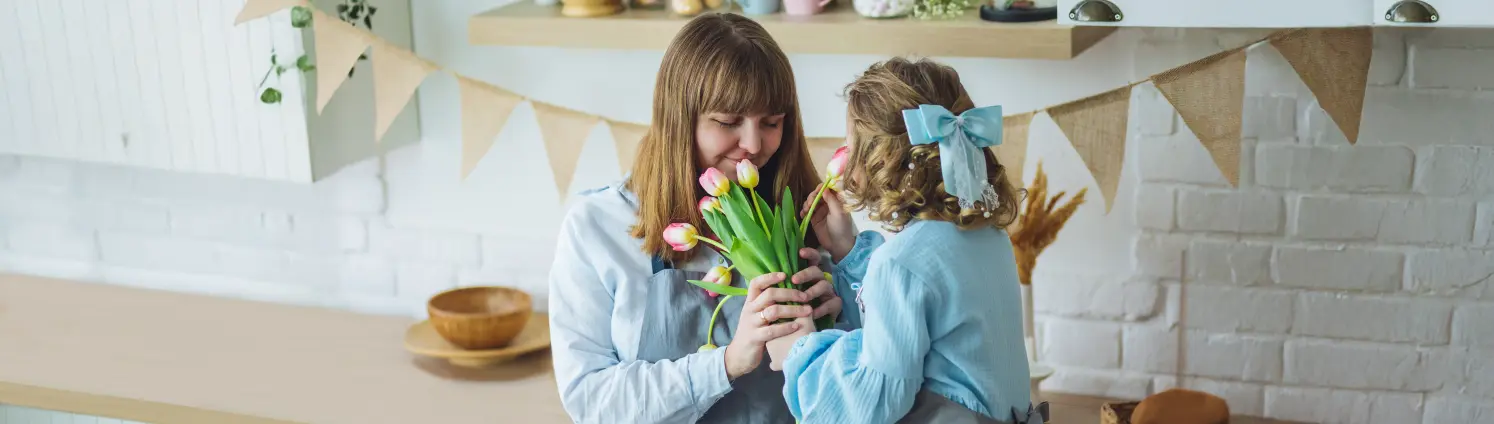 Mutter und Tochter stehen in der Küche und riechen an frischen Tulpen im Frühjahr