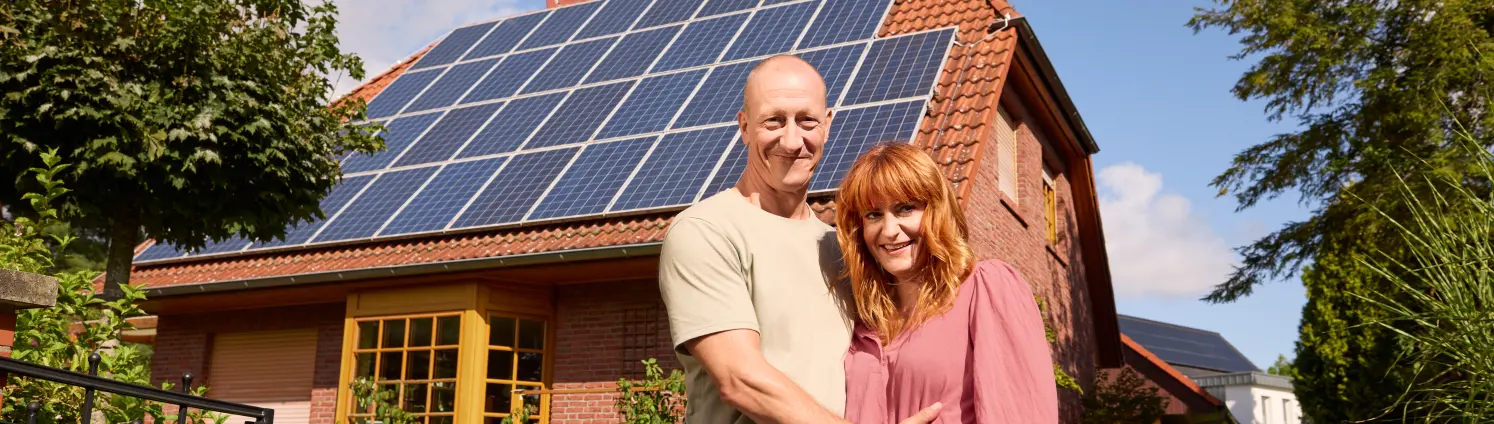 Pärchen vor ihrem Haus mit einer Photovoltaikanlage auf dem Dach