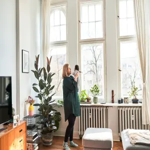 Eine Frau steht mit ihrem Baby in einem Wohnzimmer