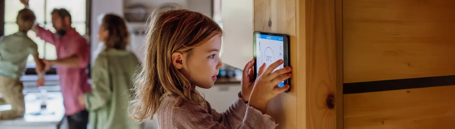 Kind steht zu Hause vor einem Thermostat