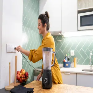 Eine Frau steckt einen Stecker in die Steckdose. 